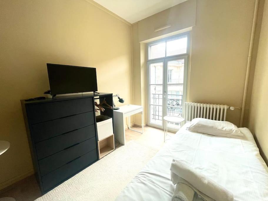 une chambre avec un lit et une commode avec une télévision dans l'établissement Studio 4 cœur de ville, à Besançon