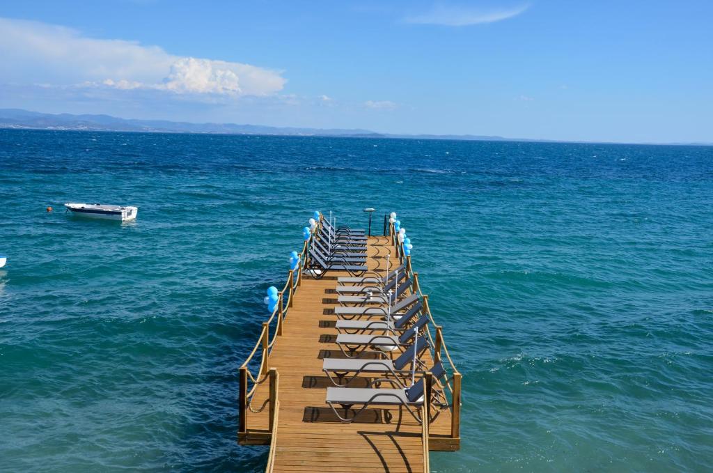einen hölzernen Pier mit Liegestühlen auf dem Wasser in der Unterkunft Lopera Beach Hotel in Edremit