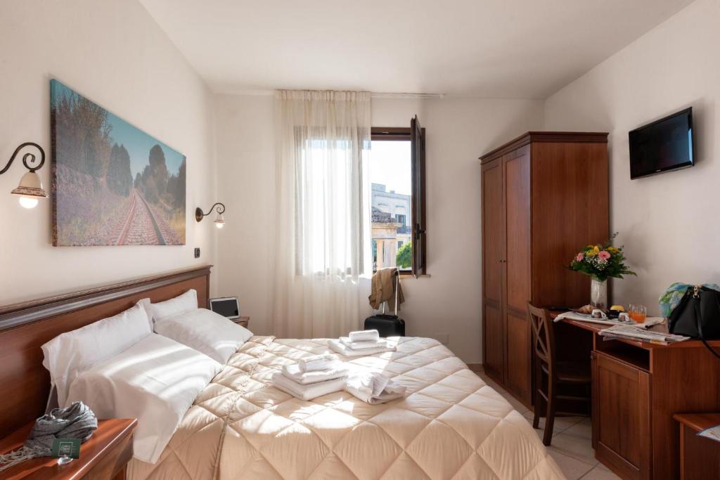 um quarto com uma cama, uma secretária e uma janela em Relais Casina Copini em Spongano