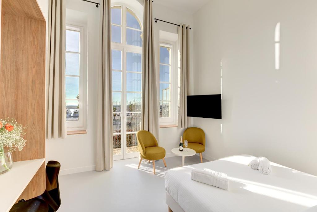 um quarto branco com uma cama, uma banheira e janelas em IMMOGROOM - Apparements luxueux - 2min du Palais - Vue mer - Clim em Cannes