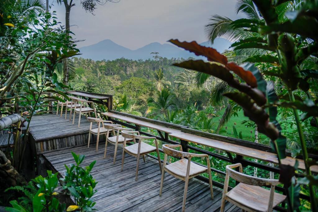 una fila de sillas sentadas en una terraza de madera en Abing Dalem - Villa Nangka en Tabanan