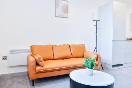 an orange couch in a living room with a table at Smart 1 Bed Apartment in Wolverhampton in Wolverhampton