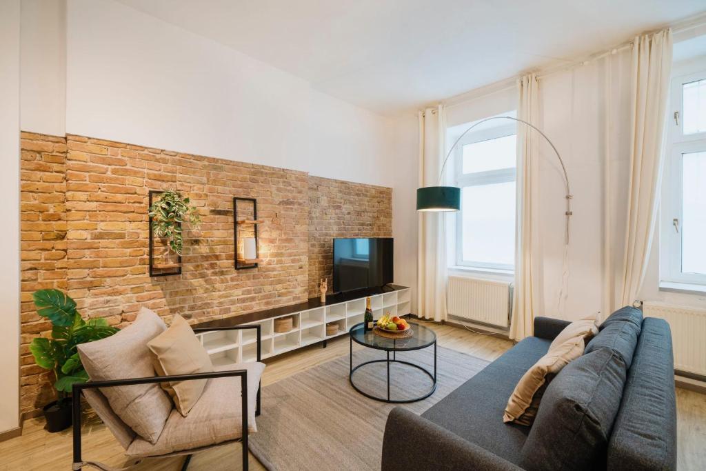 uma sala de estar com um sofá e uma parede de tijolos em NEW Luxurious Loft in central Berlin BY HOMELY em Berlim