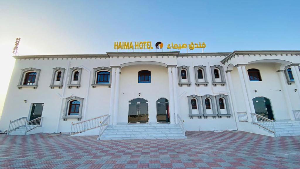 a large white building with stairs in front of it at Haima Hotel in Haymāʼ