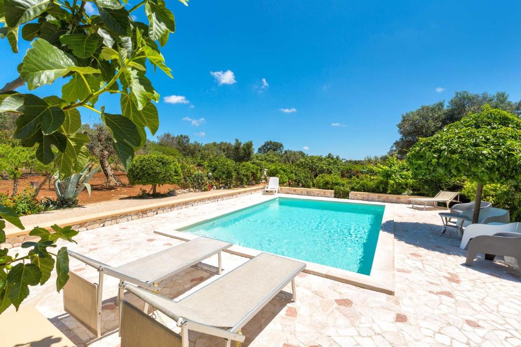 een zwembad met 2 ligstoelen en een zwembad bij Trullo Mimosa by Perle di Puglia in San Michele Salentino