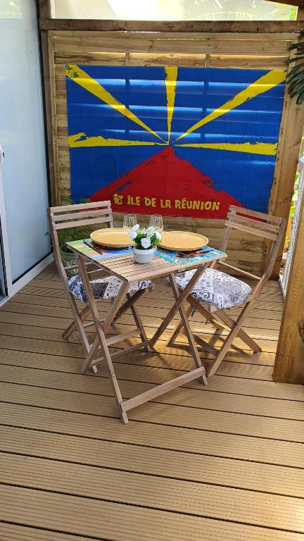 a picnic table and two chairs on a deck at Les Clairs Matins in Saint-Benoît