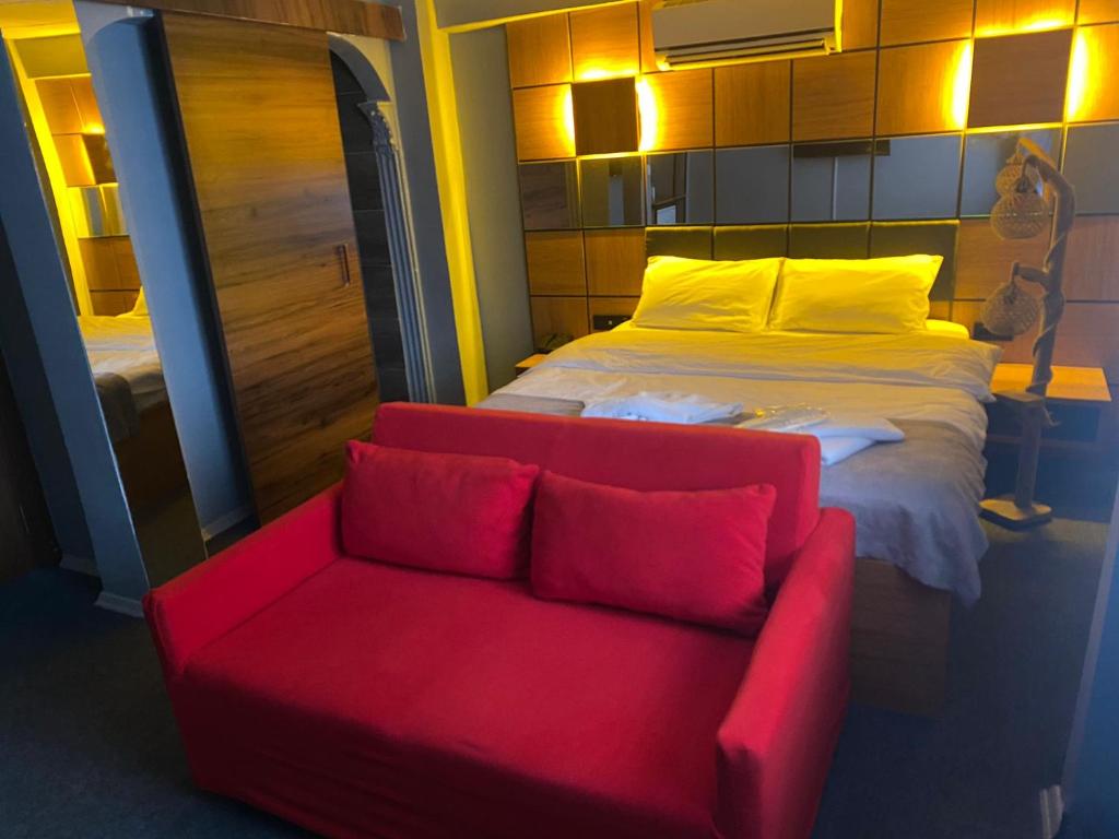 a red couch and a bed in a room at Kadıköy Linda Hotel in Istanbul