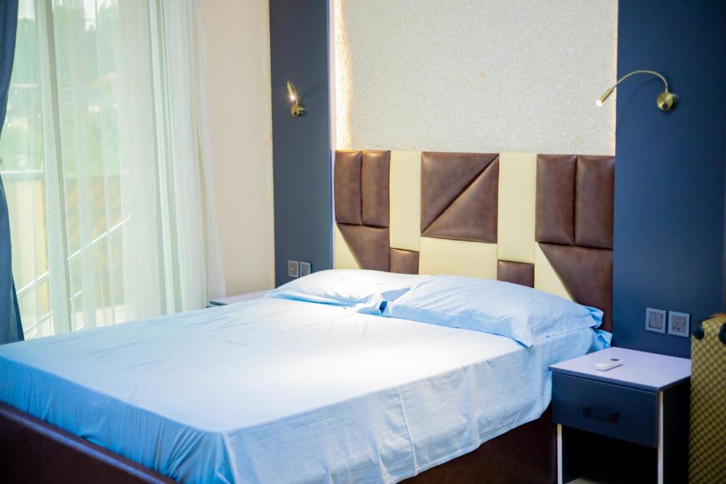 - une chambre avec un grand lit et une grande tête de lit dans l'établissement Stay Apartment, à Kigali
