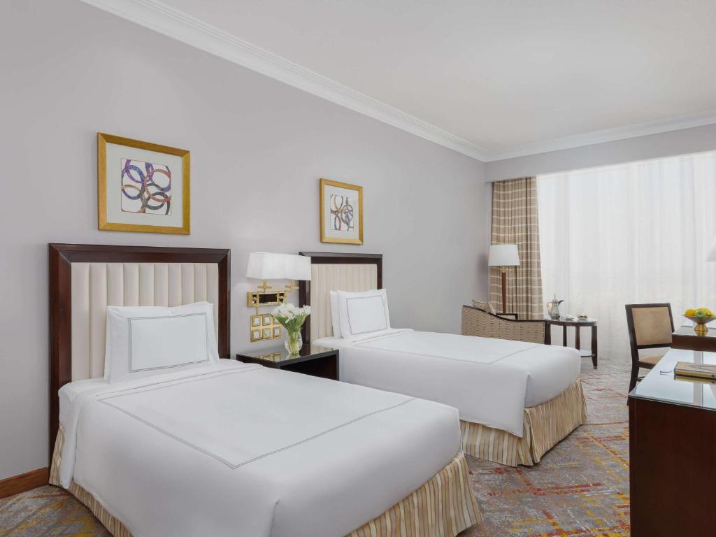 a hotel room with two beds and a desk at Swissotel Al Maqam Makkah in Mecca