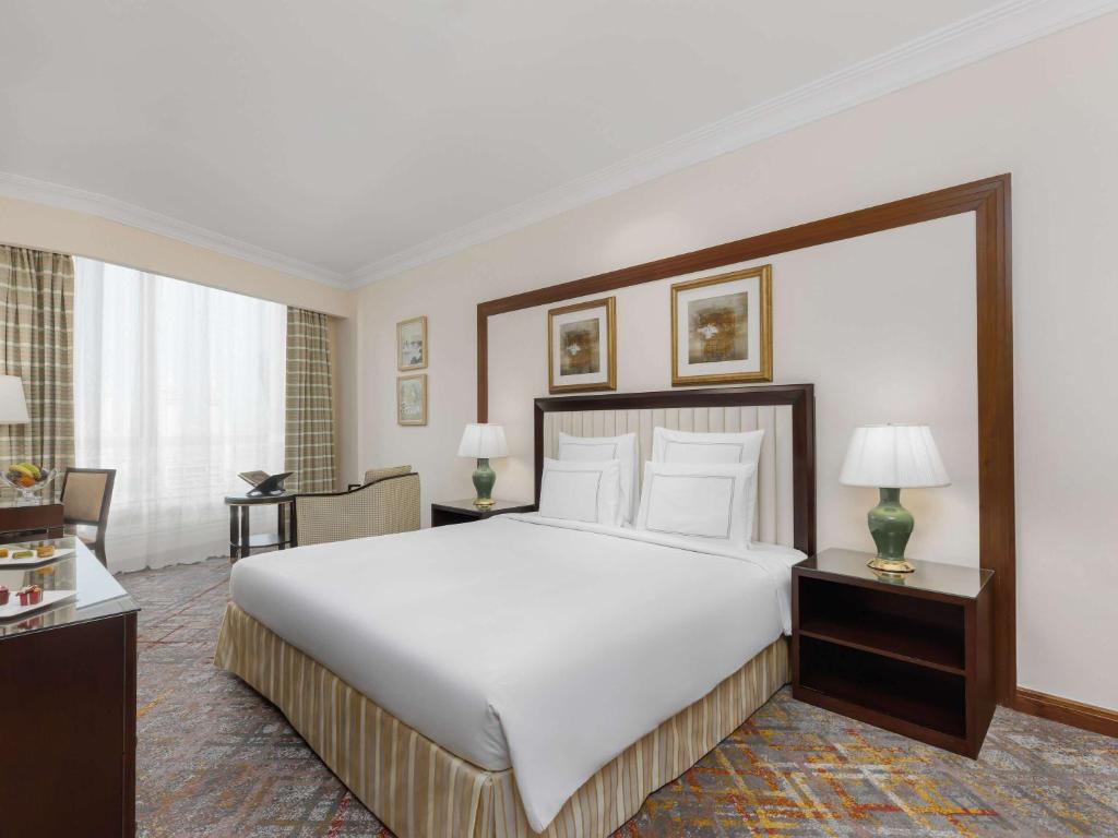 a bedroom with a large white bed and two tables at Swissotel Al Maqam Makkah in Mecca