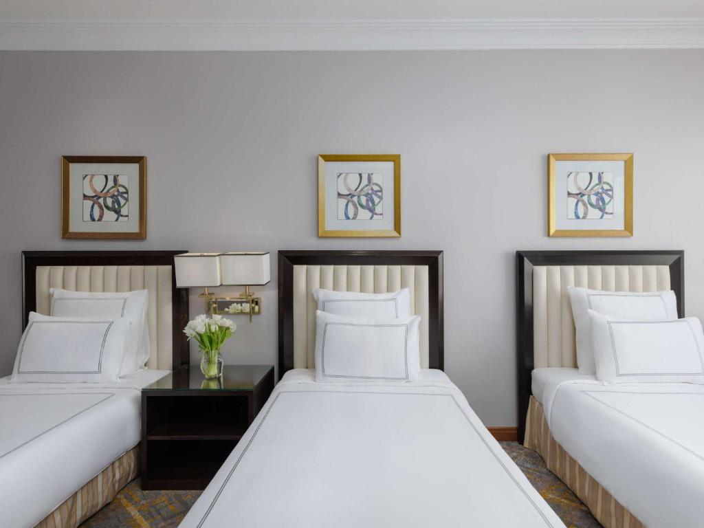 two beds in a room with white walls at Swissotel Al Maqam Makkah in Mecca