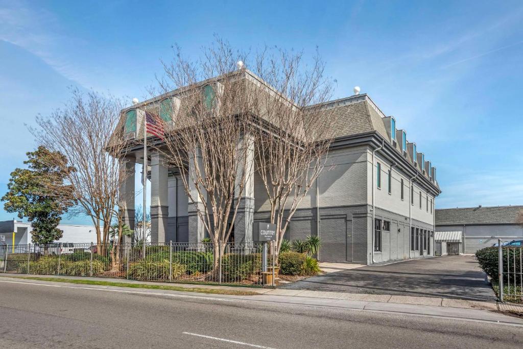 a building on the side of a street with trees at Country Inn & Suites by Radisson, Metairie New Orleans , LA in Metairie