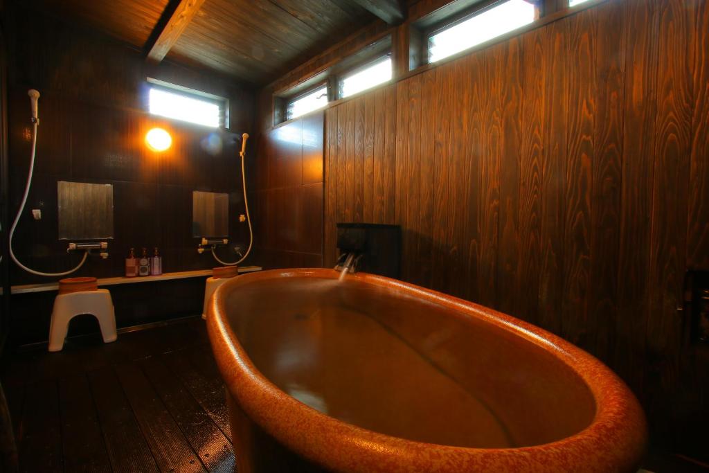 a bath tub in a bathroom with wooden walls at 旅館　松乃湯 in Kutami