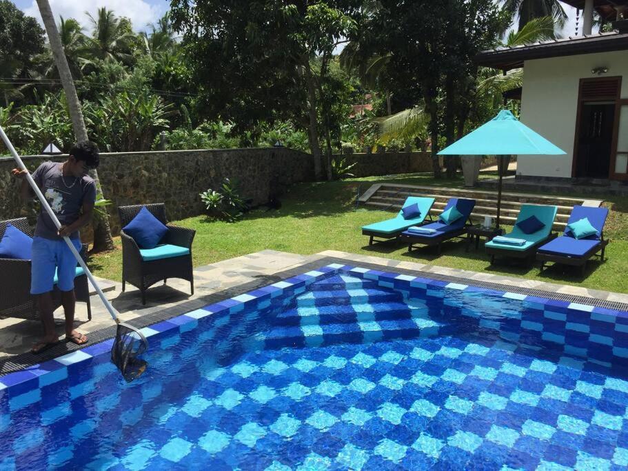 a man is cleaning a swimming pool with a mop at Koratuwa - Dickwella in Dickwella