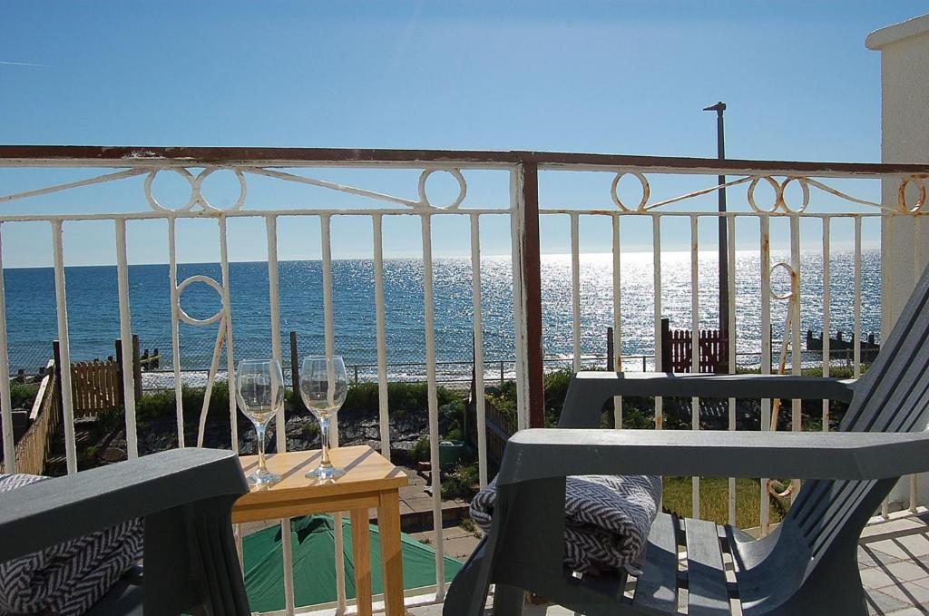 a balcony with a table and chairs and the ocean at Sunny Side Up Beach House in Tywyn in Tywyn