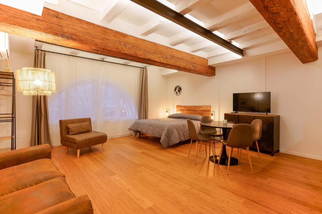 Sette Chiese Apartments في بولونيا: غرفة نوم بسرير وطاولة واريكة