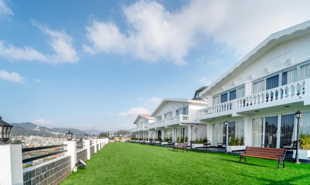 a row of white buildings with a green lawn at Treebo Trend Skydale Premium Suites - 1500 Mtrs From Ooty Lake in Ooty