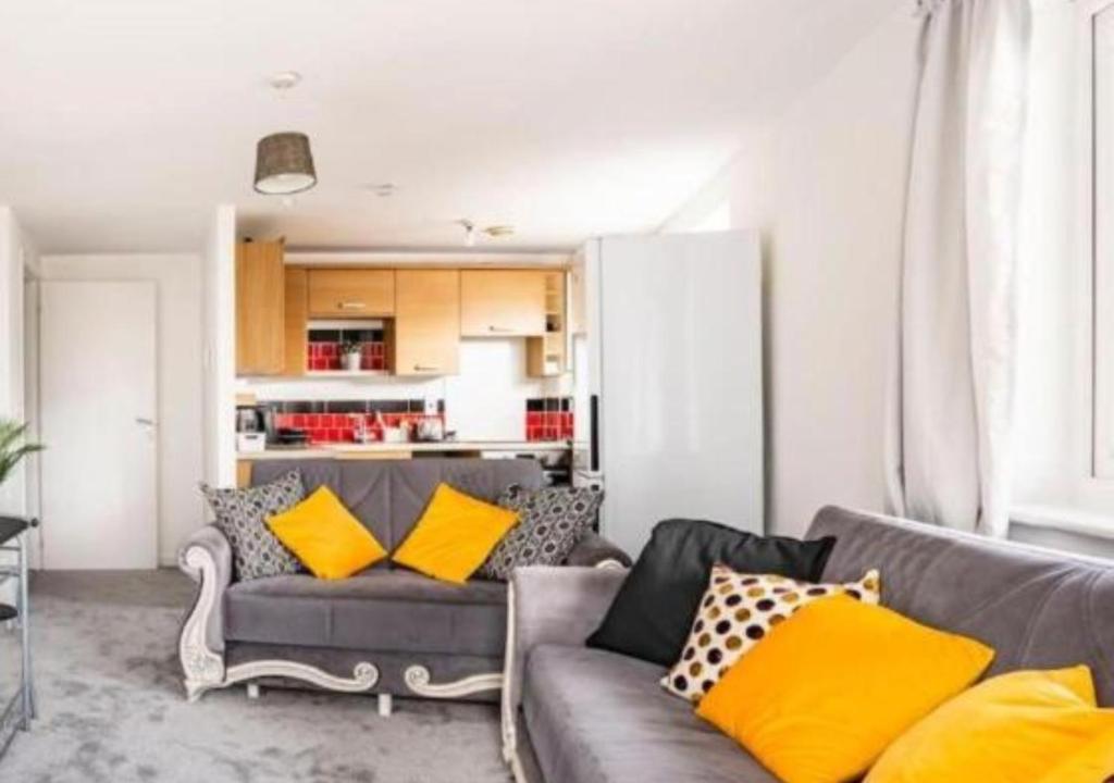 a living room with a gray couch with yellow pillows at The Dartford Lodge - Free Parking in Kent