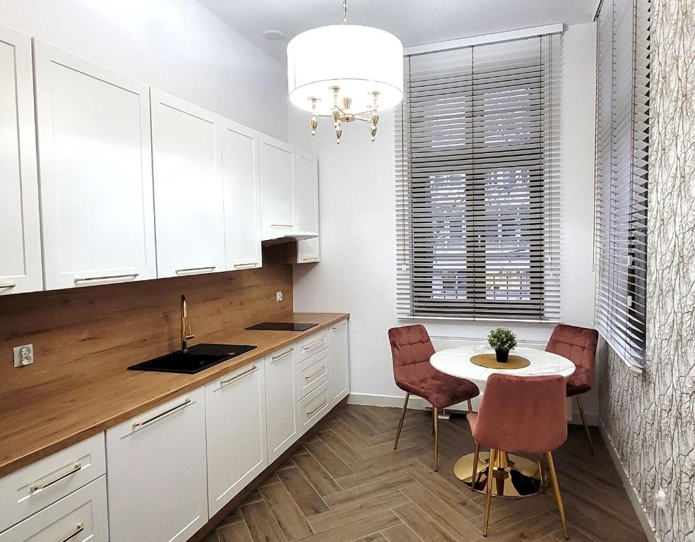 a kitchen with white cabinets and a table and chairs at APARTAMENT JARACZA 28/11 in Słupsk