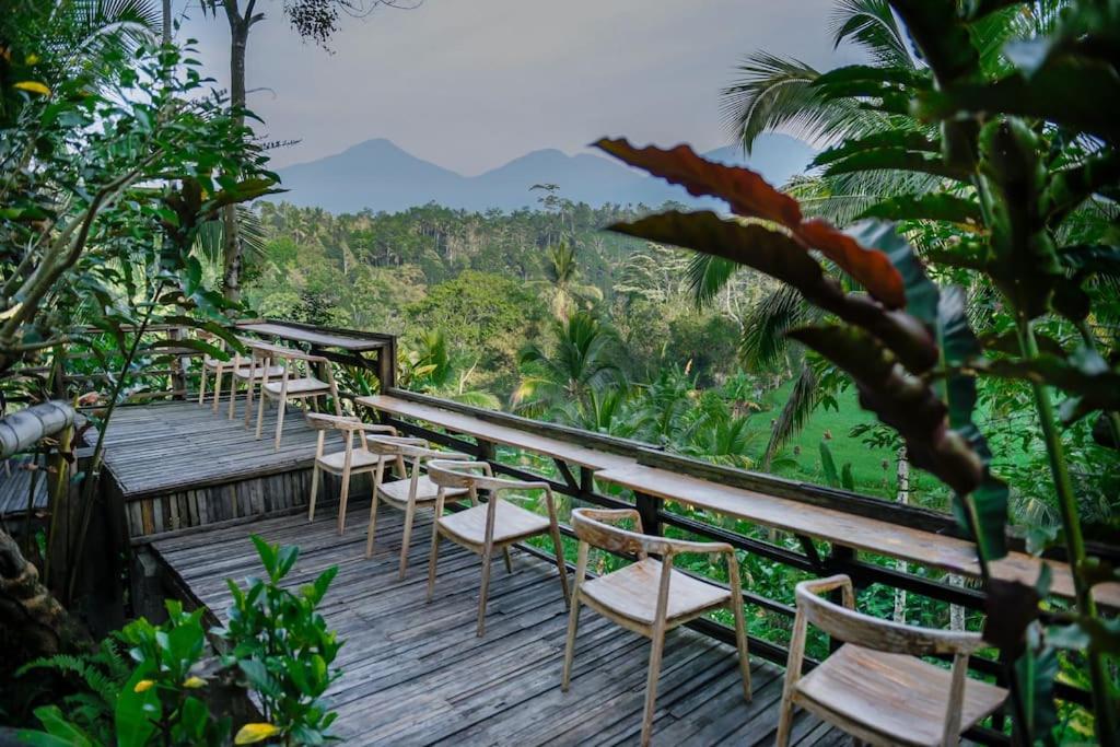 une rangée de chaises sur une terrasse en bois avec des montagnes en arrière-plan dans l'établissement Abing Dalem - Villa Mangga, à Tabanan