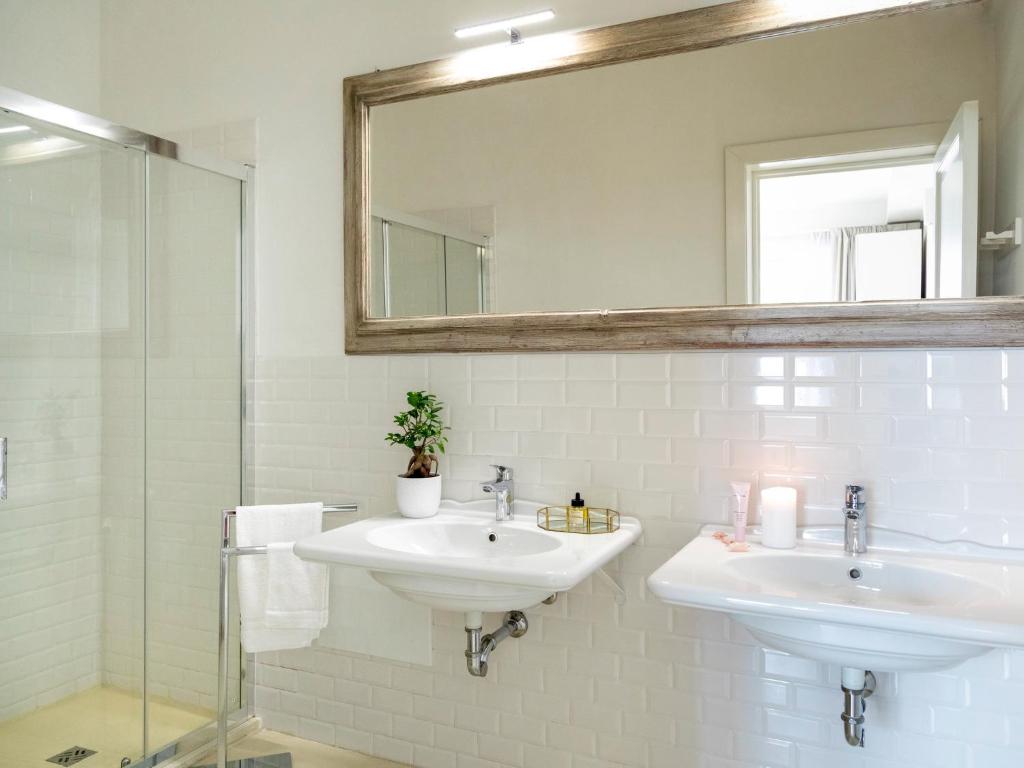 a white bathroom with two sinks and a mirror at Relais San Martino Salento - Handwritten Collection in Taviano