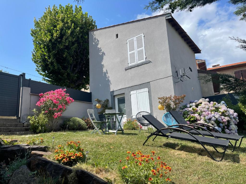 un patio con sillas y flores frente a una casa en La maisonnette de Julien - 3 étoiles, en Ceyrat