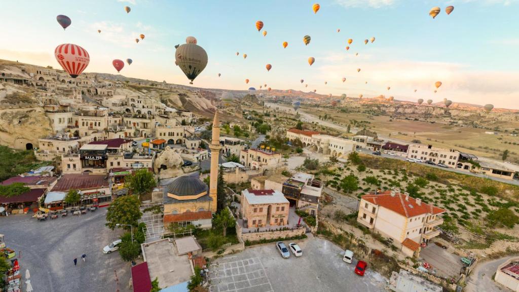 un grupo de globos de aire caliente volando sobre una ciudad en Atax Cave House en Avanos