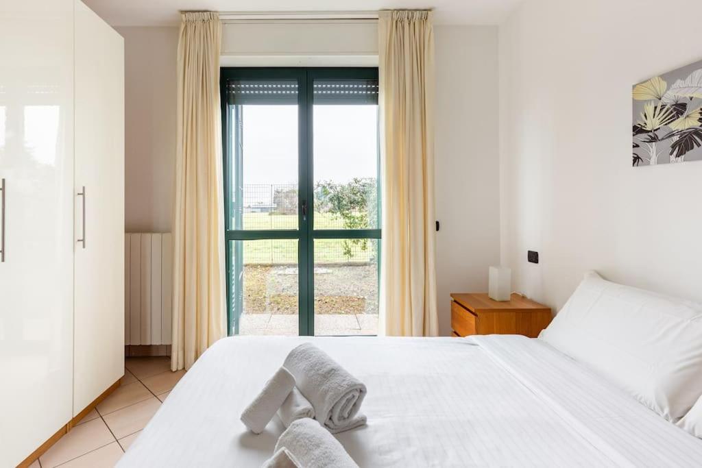 een slaapkamer met een wit bed en een groot raam bij Accogliente Bilocale con Giardino e Parcheggio in Monza