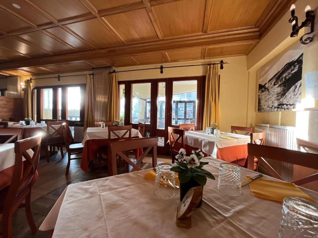 ein Esszimmer mit Tischen, Stühlen und Fenstern in der Unterkunft Hotel Togo Monte Terminillo in Monte Terminillo