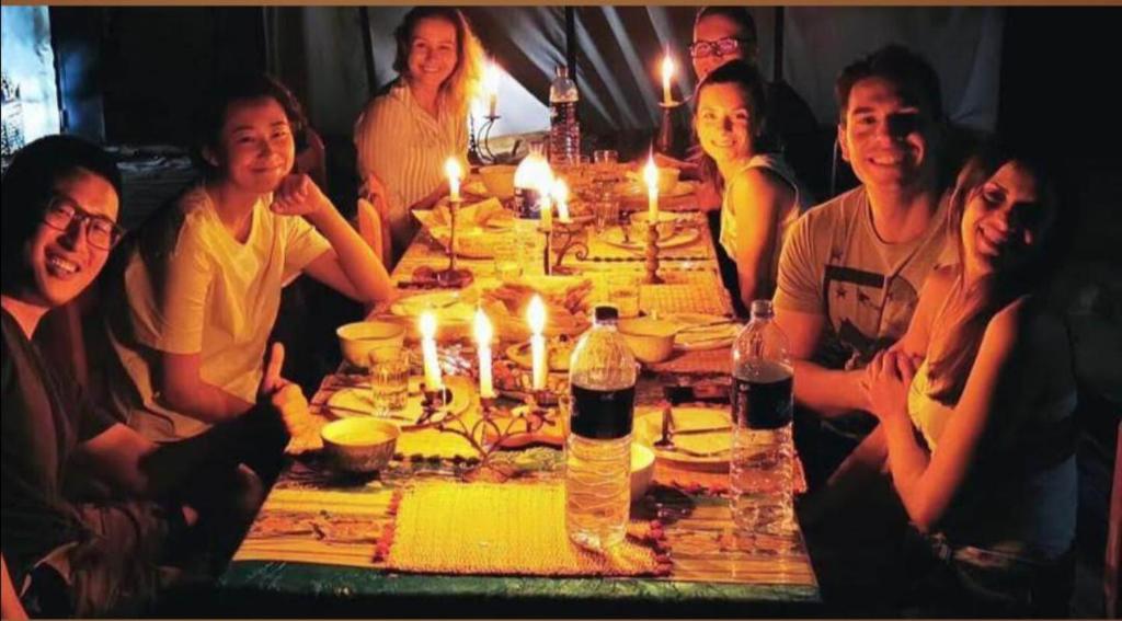 a group of people sitting around a table with lit candles at Ibra desert Camp in Merzouga