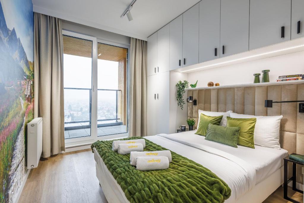 a bedroom with a large bed with a green blanket at Emihouse KrakoVska Apartments in Rzeszów