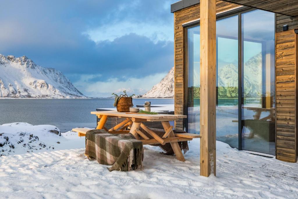 Cabaña de madera con mesa de picnic en la nieve en Nydelig hytte i unike Lofoten i nærheten av Henningsvær!, en Lyngværet