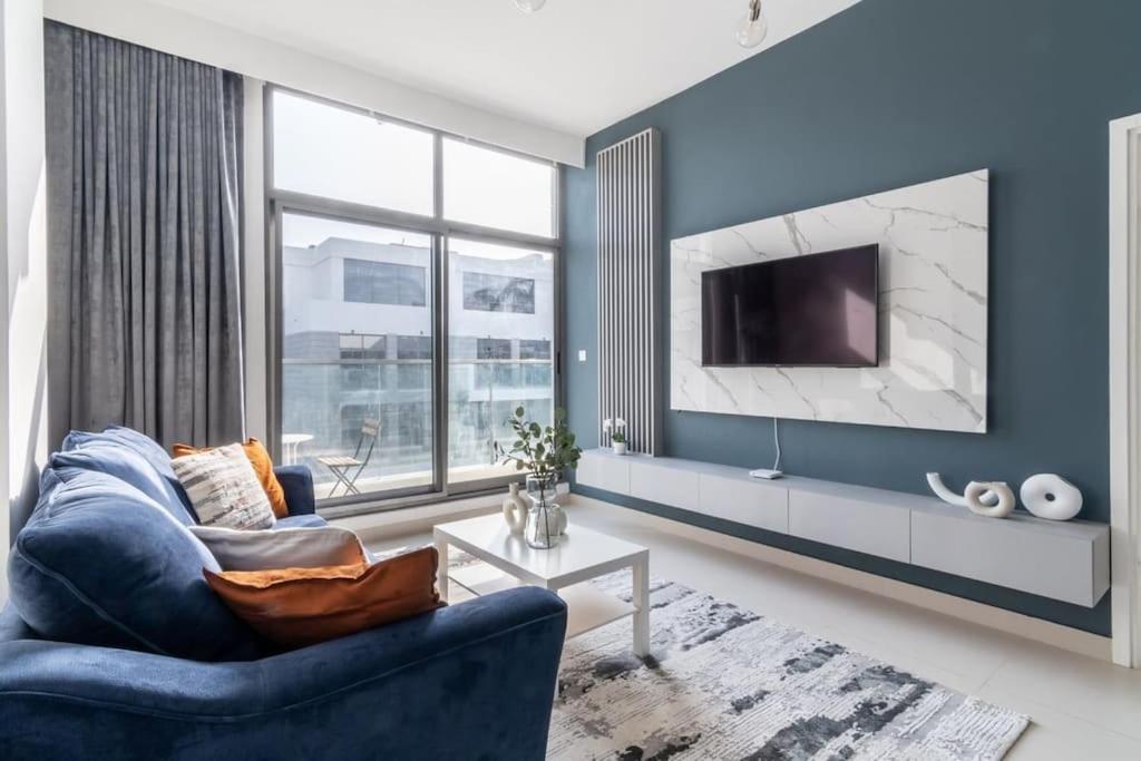 a living room with a blue couch and a tv at GuestReady - Prime Views in Dubai