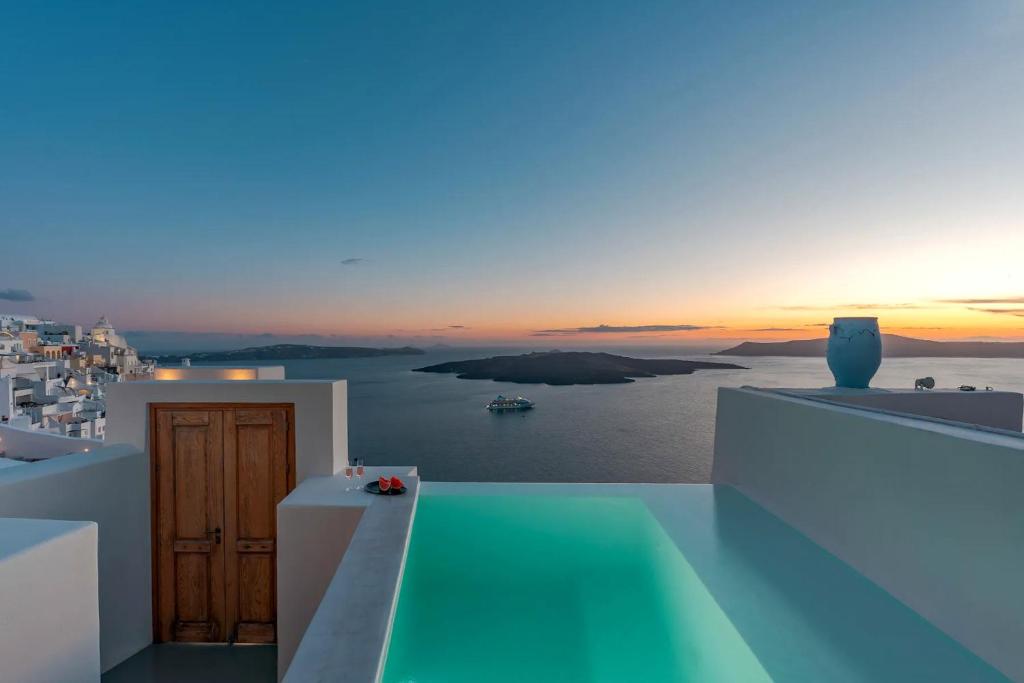a view of the ocean at sunset from a house at Luxury Grand Santorini Villa - 3 Bedrooms - Unforgettable Caldera Sea Views and Outdoor Hot Tub - Fira in Fira
