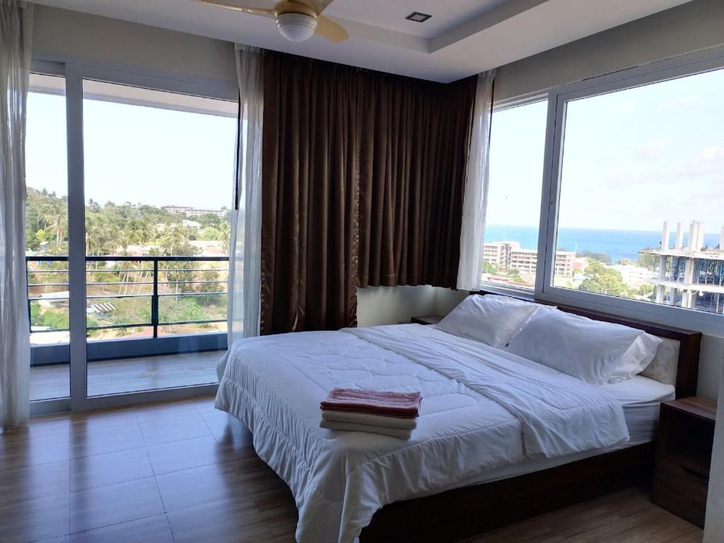 1 dormitorio con 1 cama grande y ventanas grandes en Seaside Haven Karon, en Ka Rorn