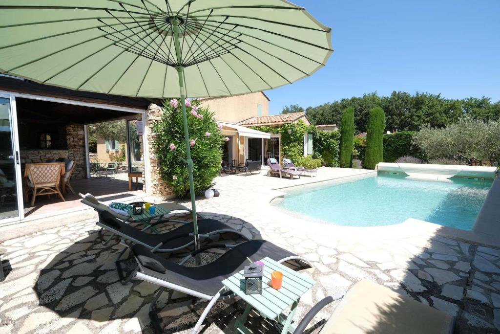 una sombrilla y sillas junto a la piscina en Very pleasant vacation rental with heated pool in the Luberon, en Gargas