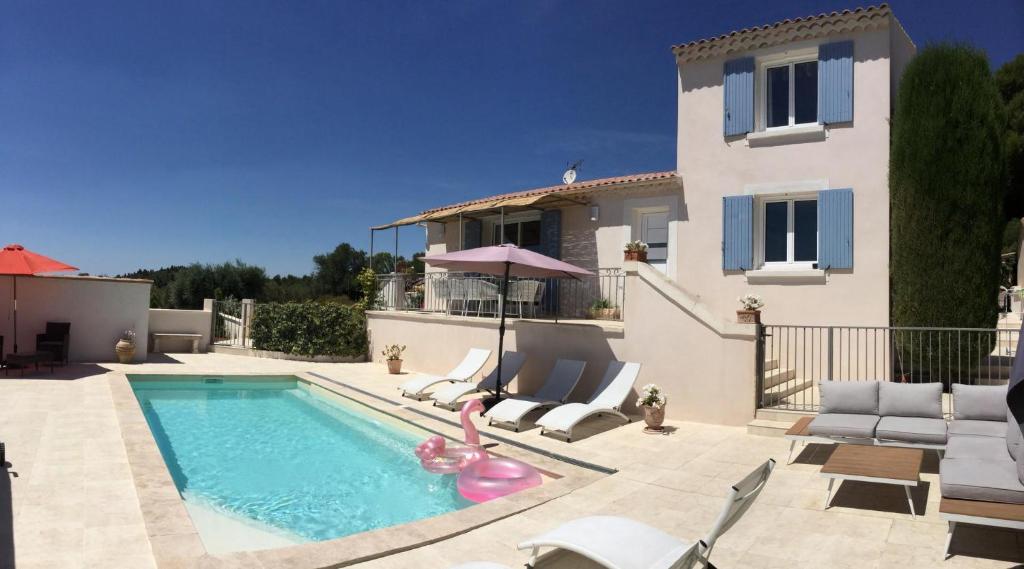 una piscina con sedie e una casa di Vacation rental in the Alpilles, Provence, close to the village center - Beautiful view -Air conditionning Heated pool and spa - sleeps 8 a Aureille