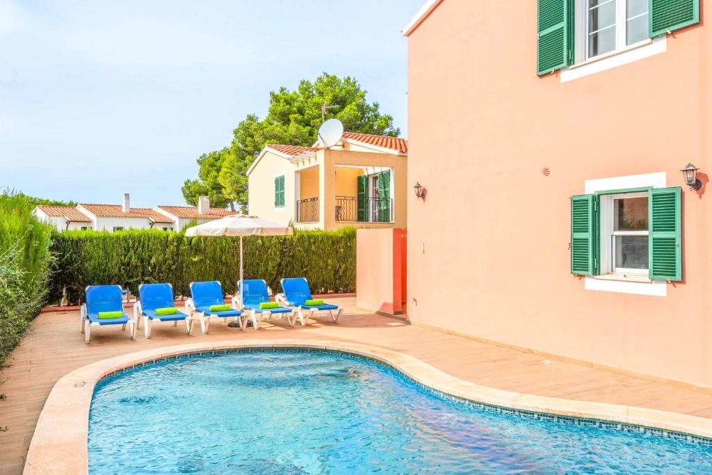 een villa met een zwembad en blauwe stoelen bij Villa Galdana Rosa in Cala Galdana