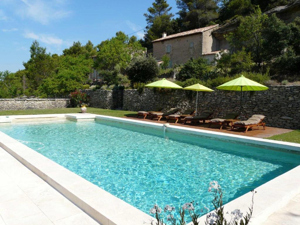 ラコステにある19th century Provencal Mas with pool in Provence in the Luberon, sleeps 6の庭園内のスイミングプール(椅子、パラソル付)