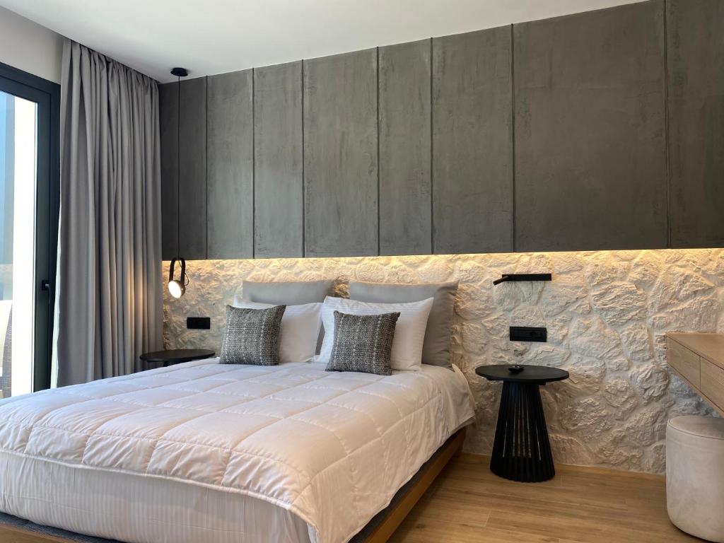 - une chambre avec un grand lit blanc et un mur dans l'établissement Tramonto Maisonettes & Suites, à Parga