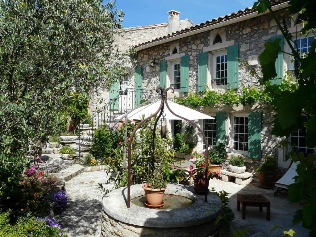 un parapluie devant une maison avec des plantes en pot dans l'établissement Semi-detached provencal farm with swimming pool, à Orgon