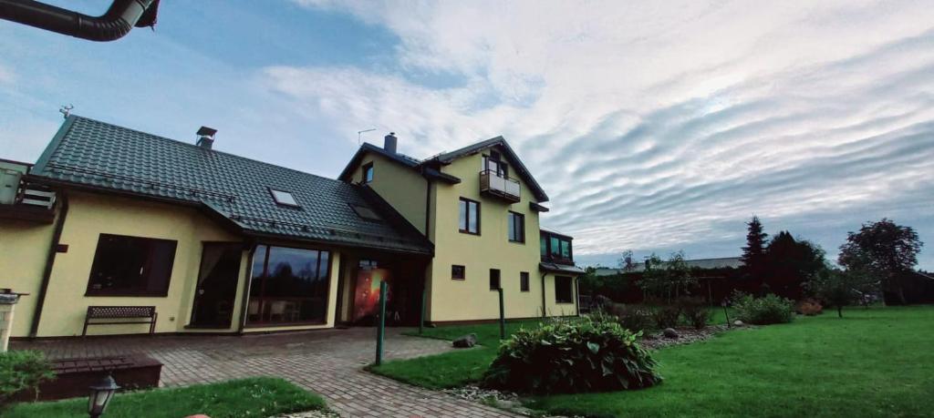 a large yellow house with a green yard at RelaxRitual in Līči