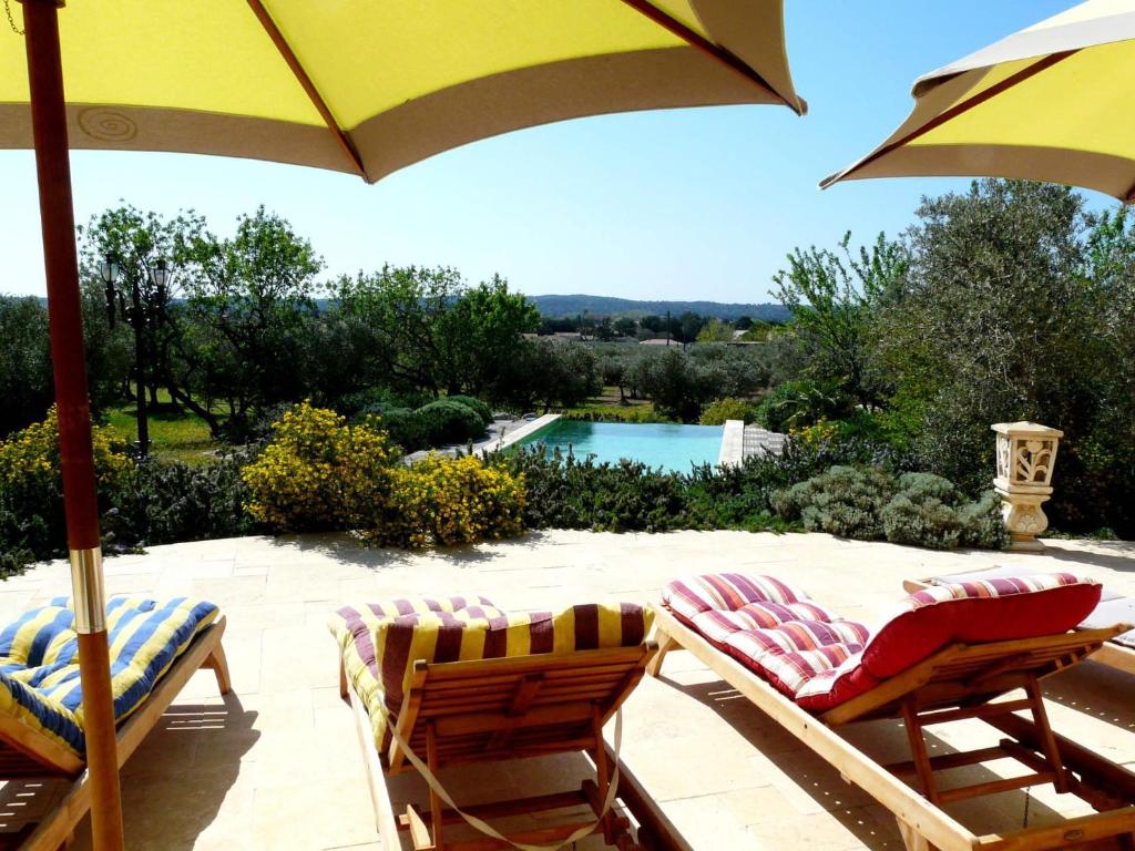 2 stoelen en een parasol op een patio met een zwembad bij luxury mas with heated pool in the heart of the alpilles, 10 persons in Mouriès