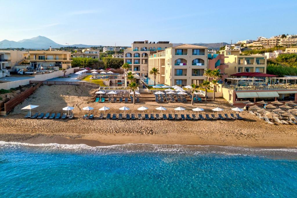 eine Luftansicht auf einen Strand mit Sonnenschirmen und dem Meer in der Unterkunft White Olive Elite Rethymno in Sfakaki