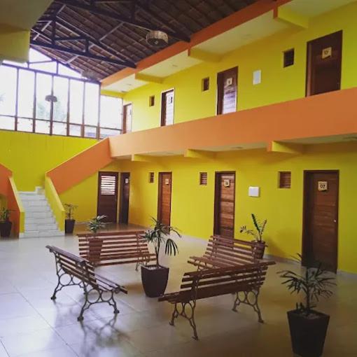 een groep banken in een gebouw met gele muren bij pousada e balneário parque das aguas in Umari