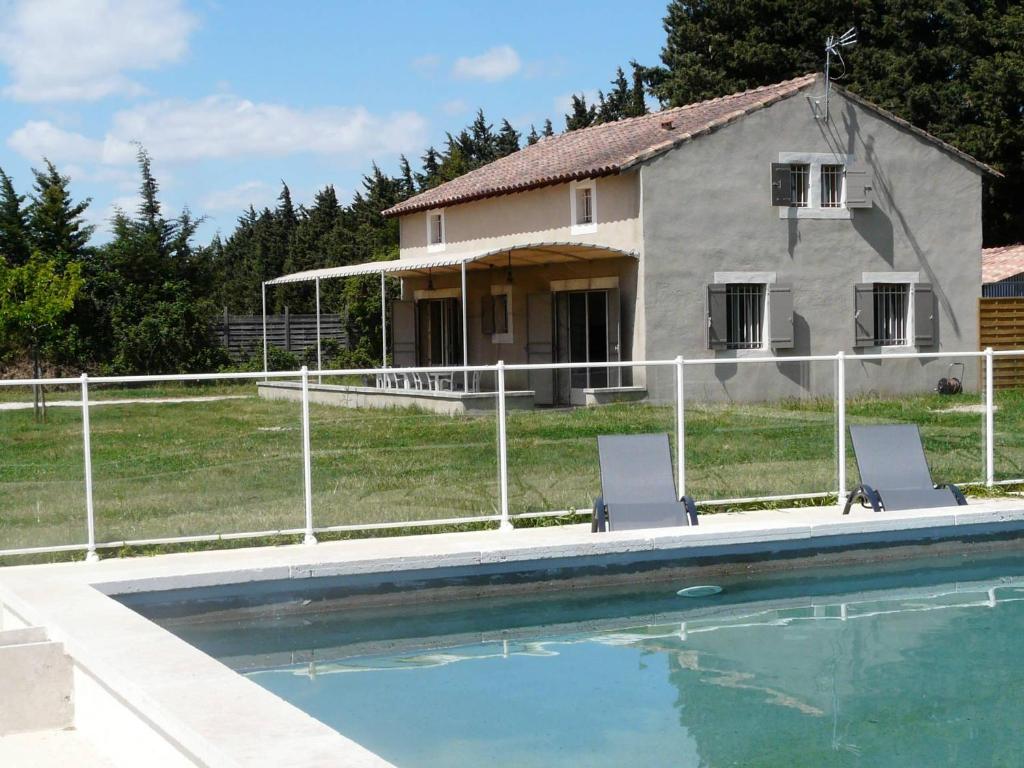 une maison et une piscine avec deux chaises dans l'établissement air-conditioned family house with fenced pool in fontvieille in the alpilles, sleeps 8, à Fontvieille