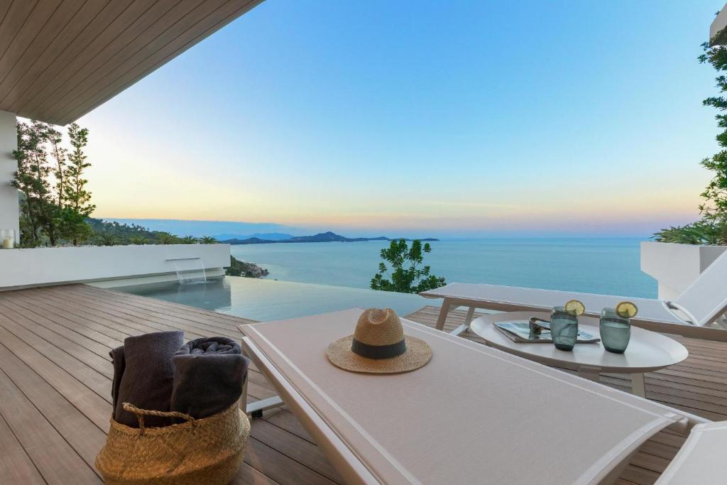ein Tisch mit einem Hut auf einem Balkon mit Blick auf das Meer in der Unterkunft Sukkho Samui Estates in Strand Chaweng Noi