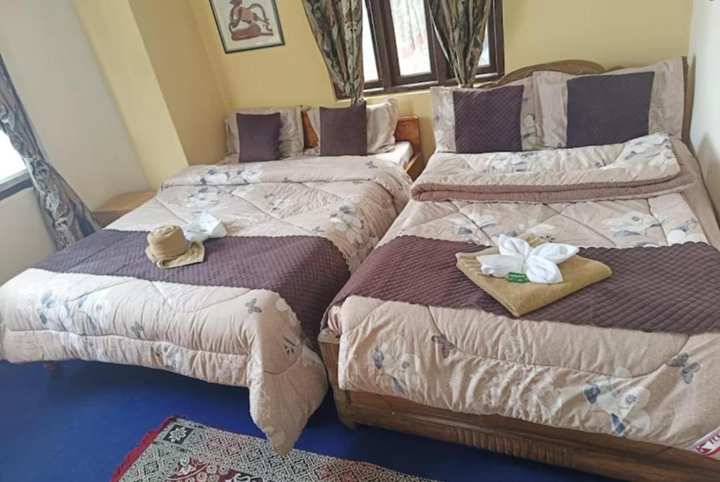 2 camas con sombreros y toallas en una habitación en GRG Mountview By Darjeeling, en Darjeeling