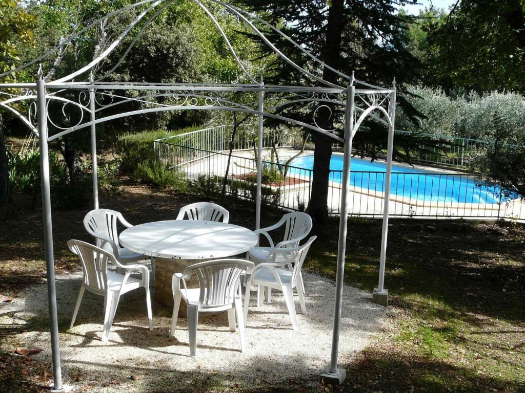 ein weißer Tisch und Stühle unter einem Baldachin neben einem Pool in der Unterkunft Spacious villa on two levels in Cabrières-dʼAvignon