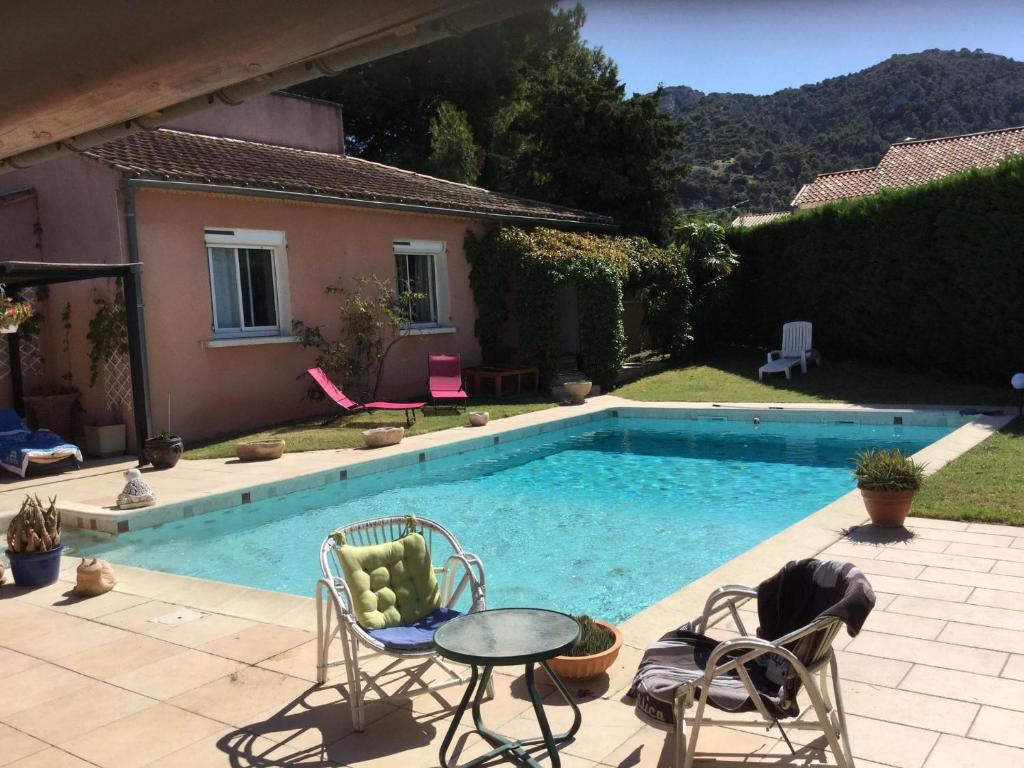 a swimming pool with chairs and a table next to a house at beautiful vacation home with pool located in robion with a pretty view on the luberon. 8 people. in Robion en Luberon